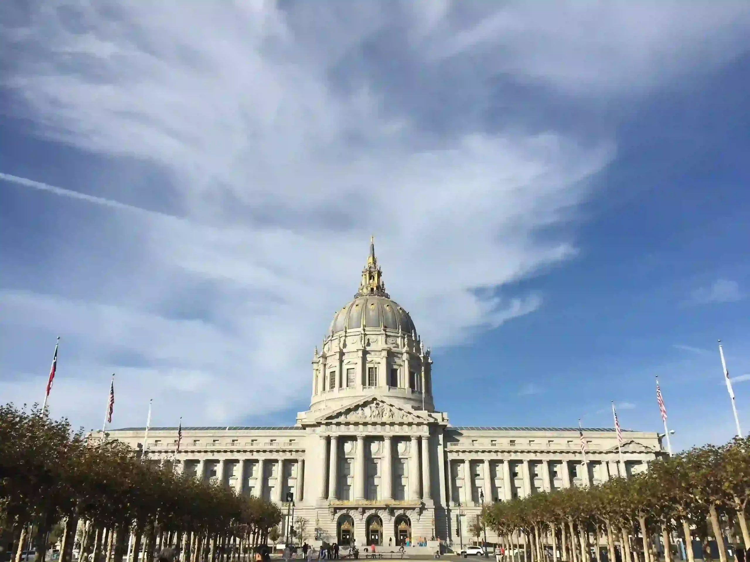 A civic government building with a domed roof and colonnaded facade under a clear sky
